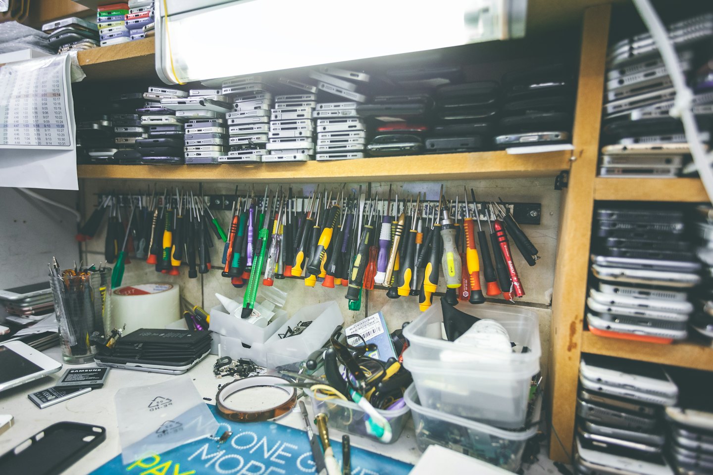 Electronics repair workstation with tools and stacked mobile devices.