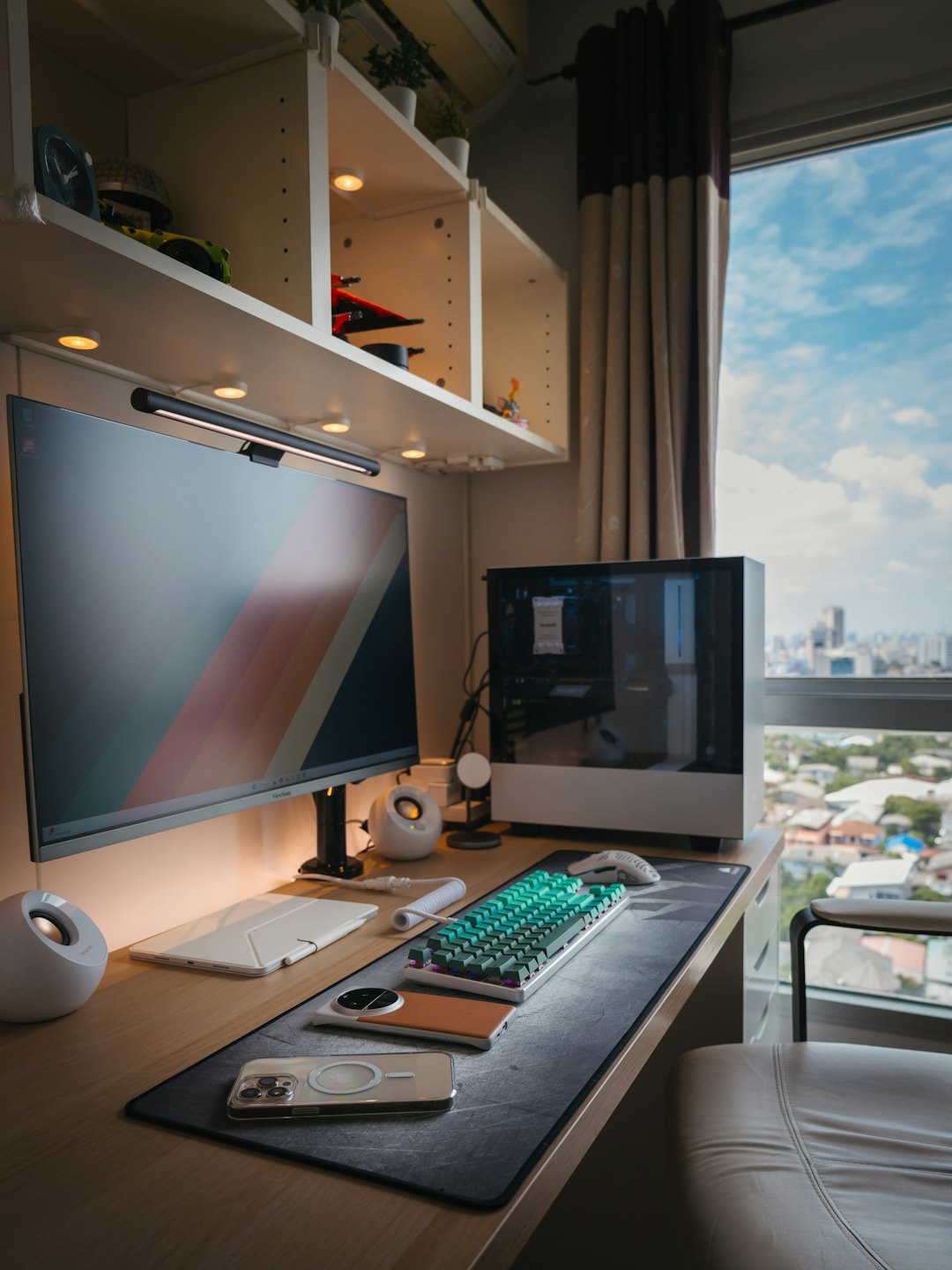Modern computer workstation placed by a window overlooking a city.